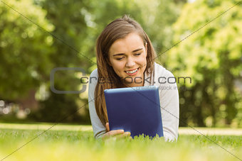 Smiling university student lying and using tablet pc
