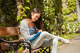 Smiling student sitting on bench and writing on notepad