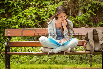 Smiling student sitting on bench reading book