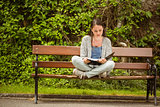 Student sitting on bench listening music with mobile phone and revising