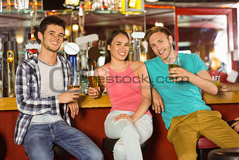 Smiling friends drinking beer together
