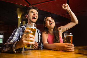 Happy friends drinking beer and cheering together