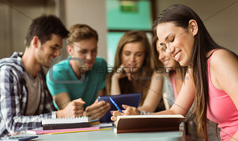 Smiling friends sitting studying and using tablet pc