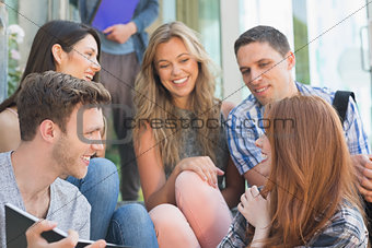 Happy students looking at book outside on campus