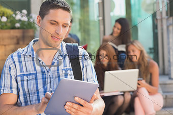 Happy student using his tablet pc on campus