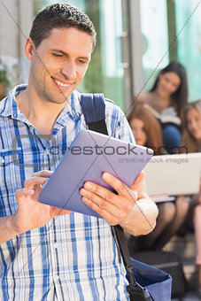Happy student using his tablet pc on campus