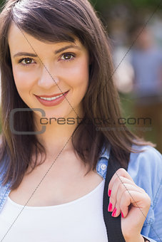 Pretty student smiling at camera outside on campus