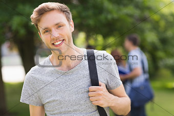 Handsome student smiling at camera outside on campus