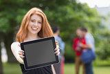 Pretty student smiling at camera using tablet pc