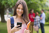 Happy student sending a text outside on campus