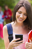 Pretty student sending a text outside on campus