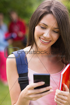 Pretty student sending a text outside on campus