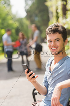 Handsome student sending a text outside