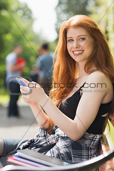 Pretty student sending a text outside