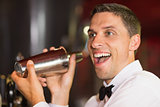 Handsome barman smiling at camera making a cocktail