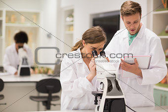 Happy medical students working with microscope