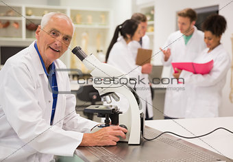 Smiling medical professor working with microscope