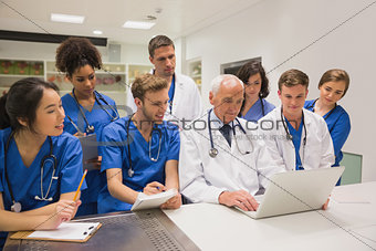 Medical students and professor using laptop