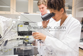 Pretty science student using microscope