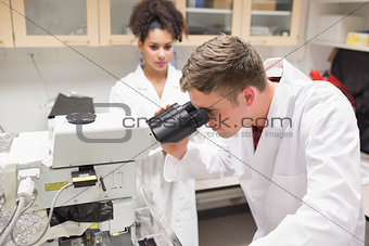 Young scientist working with microscope