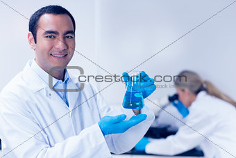 Science student holding blue chemical in beaker