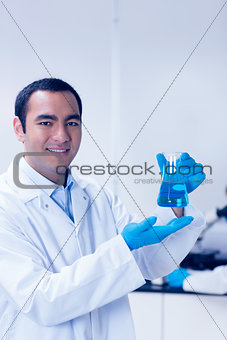 Science student holding blue chemical in beaker