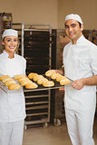 Team of bakers holding rack of rolls