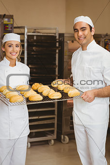 Team of bakers holding rack of rolls