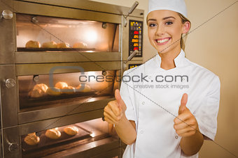 Baker smiling at camera beside oven