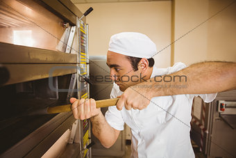 Baker taking bread out of oven