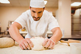 Baker kneading dough at a counter