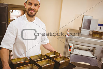 Happy baker holding tray of loaf tins