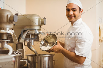 Baker pouring flour into large mixer