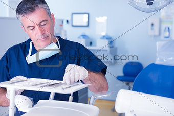 Focused dentist picking up tool