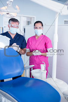 Dentist and assistant in surgical mask and protective glasses