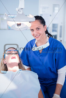 Dentist smiling at camera with patient in the chair