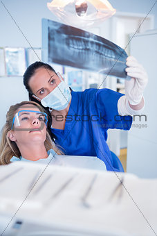 Dentist in mask explaining x-ray to patient