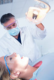 Dentist examining a patients teeth in chair under bright light
