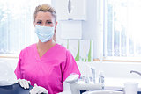 Portrait of a dentist in mask looking at camera beside chair