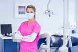 Dentist in pink scrubs looking at camera with arms crossed