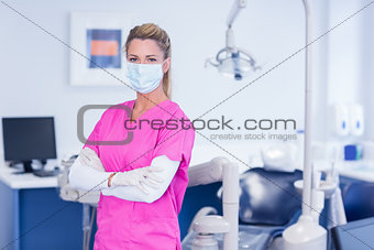 Dentist in pink scrubs looking at camera with arms crossed