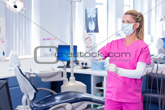 Dentist in surgical mask holding an x-ray