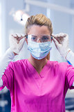 Dentist in pink scrubs looking at camera in mask and gloves