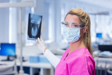 Dentist in pink scrubs holding an x-ray and looking at camera