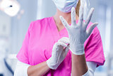 Dentist in pink scrubs putting on surgical gloves
