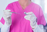 Dentist in pink scrubs holding tool