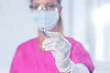 Dentist in surgical mask and scrubs holding tool