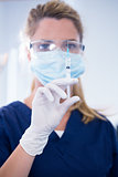 Dentist in mask and glove holding an injection