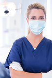 Dentist in mask looking at camera with arms crossed