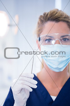 Dentist in mask holding dental explorer
